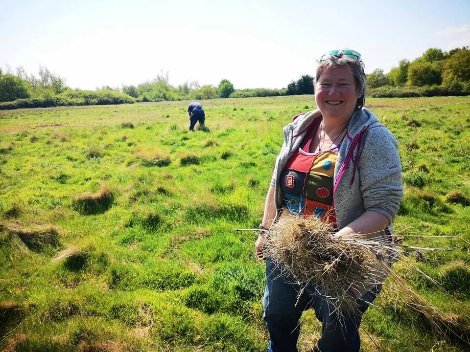 A participant gathering natural materials in a meadow