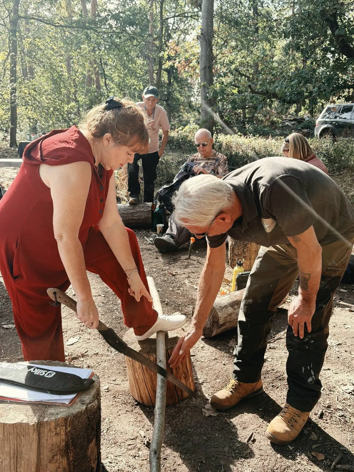 Participants working together on a bow-drill fire-lighting challenge